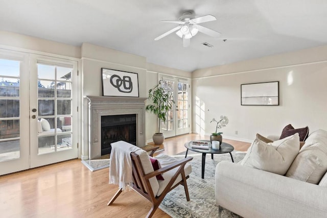 living room with french doors, ceiling fan, and light wood-type flooring