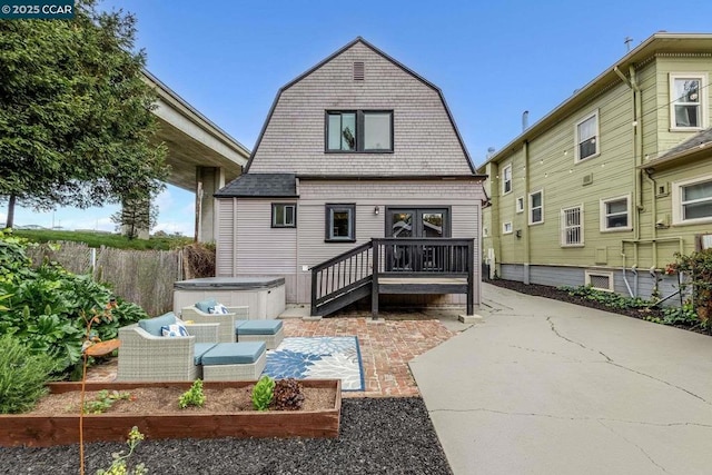 rear view of property featuring an outdoor hangout area, a patio area, and a hot tub