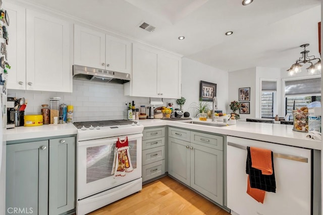 kitchen featuring tasteful backsplash, sink, white appliances, white cabinetry, and light wood-type flooring