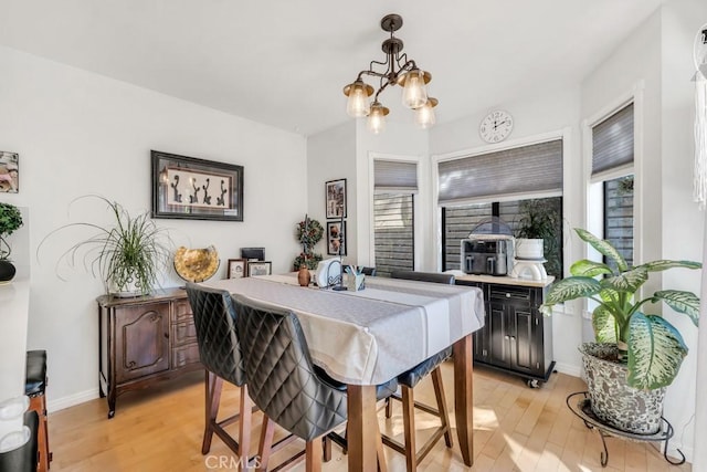 dining area featuring light wood-type flooring and an inviting chandelier