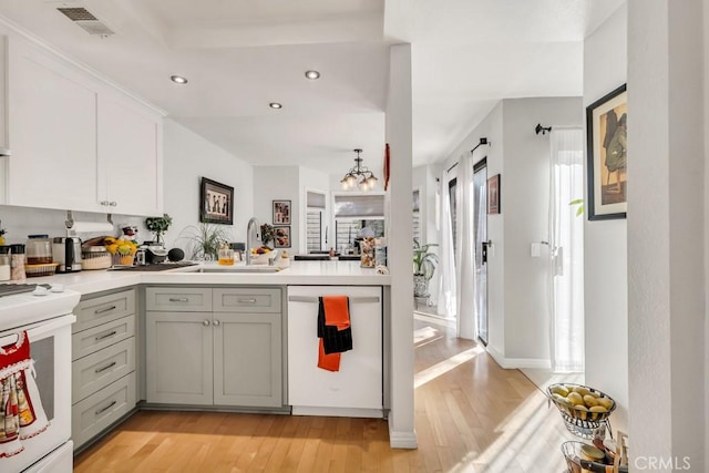 kitchen with sink, white appliances, a chandelier, and light hardwood / wood-style flooring