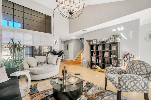 living room with a notable chandelier, a high ceiling, and hardwood / wood-style floors