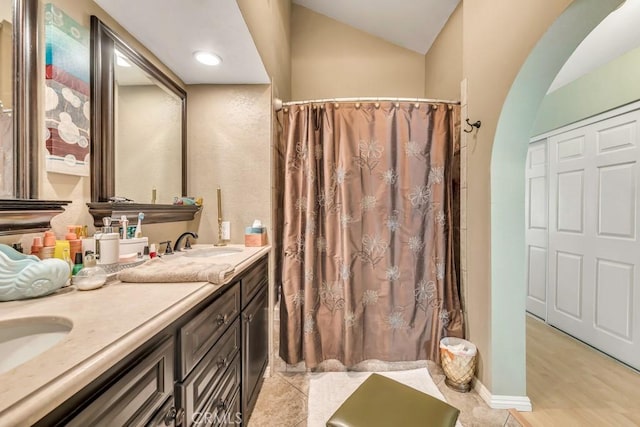 bathroom featuring lofted ceiling, vanity, and walk in shower