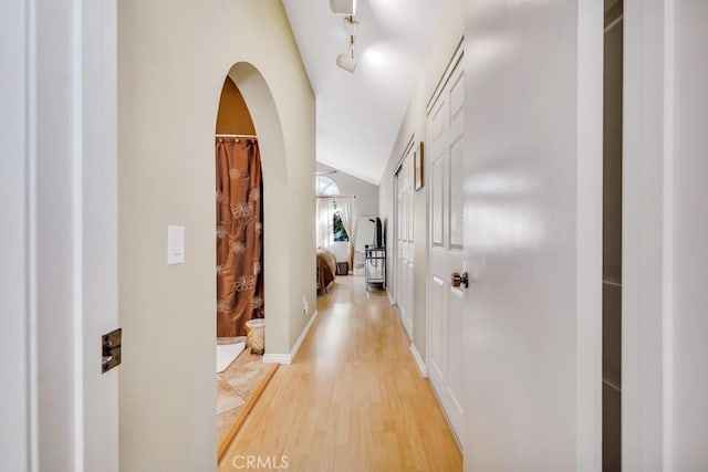 hallway featuring vaulted ceiling and light hardwood / wood-style floors