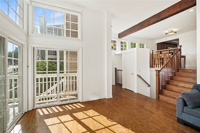 interior space featuring beam ceiling, a wealth of natural light, and hardwood / wood-style flooring