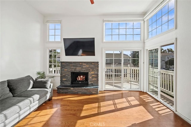 living room featuring a towering ceiling, hardwood / wood-style flooring, and a stone fireplace