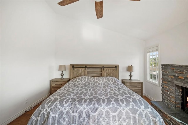 bedroom featuring ceiling fan, dark wood-type flooring, lofted ceiling, and a fireplace