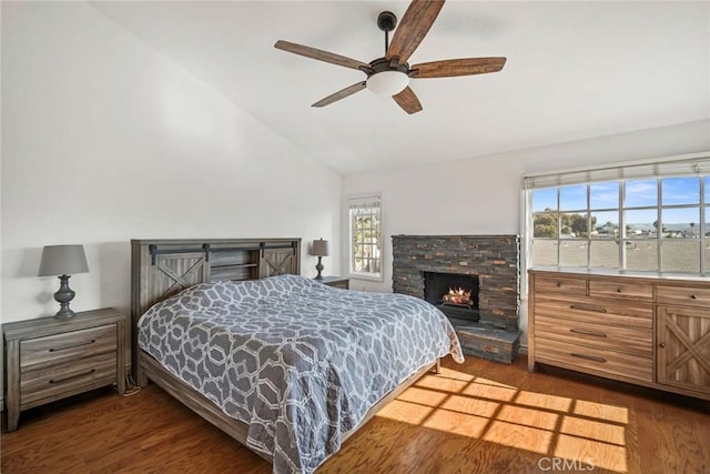 bedroom with ceiling fan, lofted ceiling, a fireplace, and dark hardwood / wood-style floors