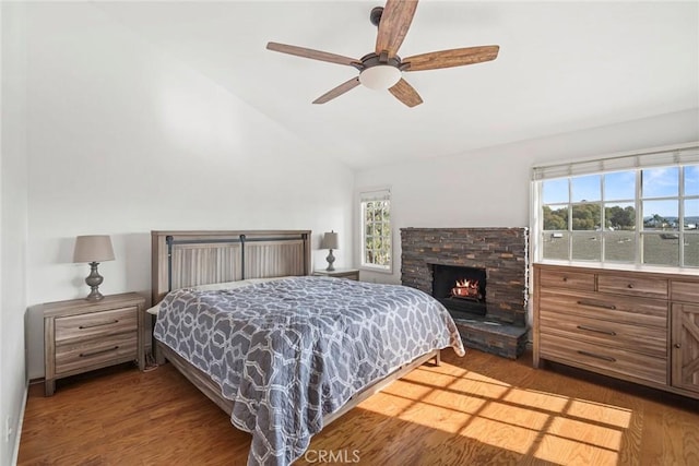 bedroom featuring ceiling fan, dark wood-type flooring, a fireplace, and lofted ceiling