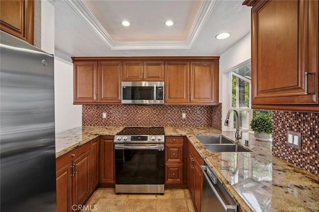 kitchen with tasteful backsplash, a raised ceiling, sink, light stone countertops, and appliances with stainless steel finishes