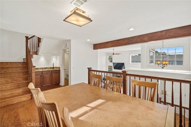 dining space with ceiling fan with notable chandelier, beam ceiling, light hardwood / wood-style floors, and sink