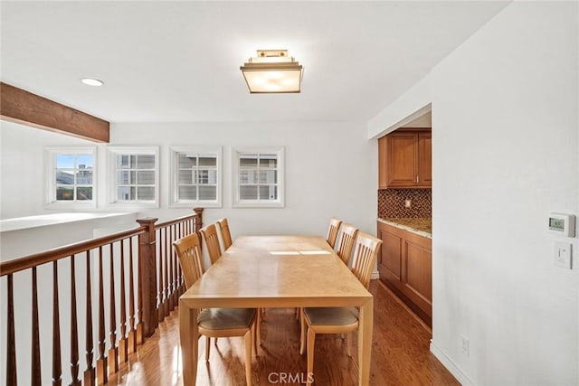 dining space with light wood-type flooring and beamed ceiling