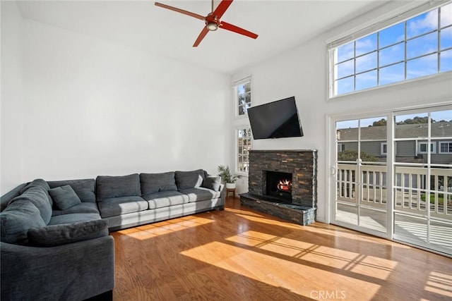 living room featuring a high ceiling, ceiling fan, a fireplace, and hardwood / wood-style flooring