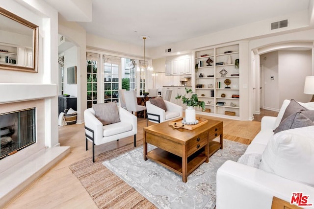 living room with light wood-type flooring and a notable chandelier