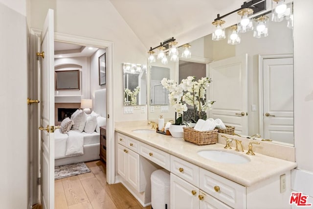 bathroom with wood-type flooring, vanity, and vaulted ceiling