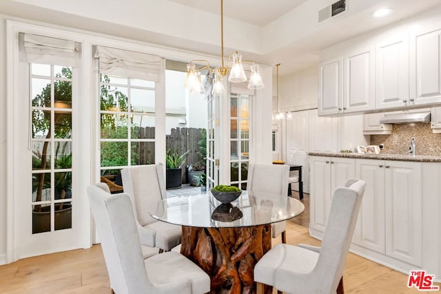 dining room featuring a notable chandelier, sink, and light hardwood / wood-style flooring