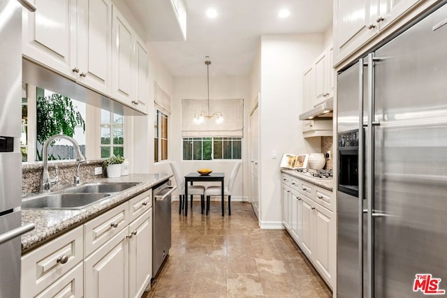 kitchen featuring light stone countertops, sink, stainless steel appliances, and white cabinetry