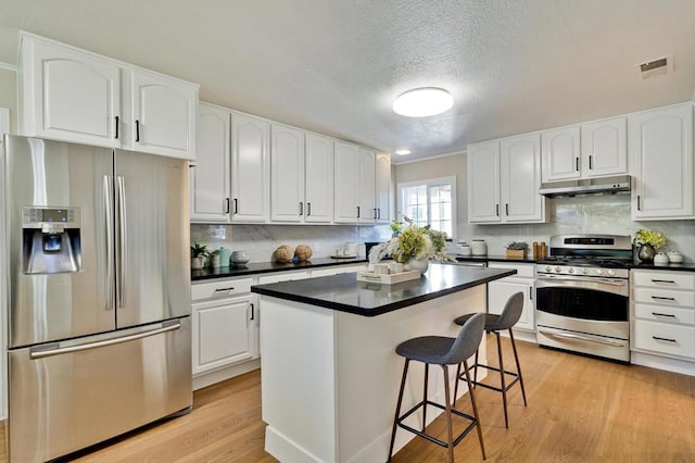 kitchen with white cabinetry, appliances with stainless steel finishes, light hardwood / wood-style floors, and a kitchen island