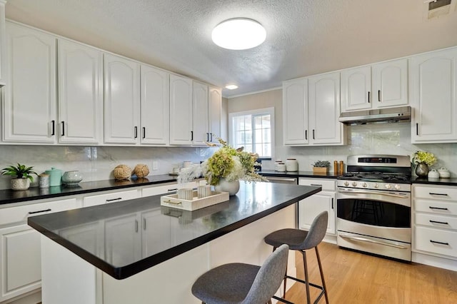 kitchen featuring white cabinetry, gas range, a textured ceiling, and a kitchen island