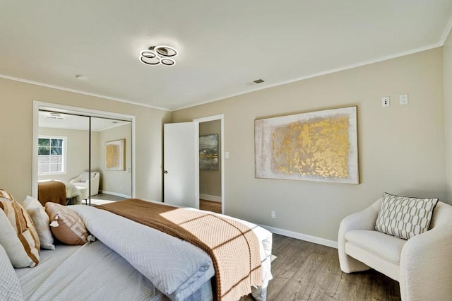 bedroom with hardwood / wood-style flooring, crown molding, and a closet