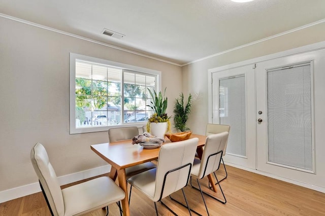 dining area featuring ornamental molding, light hardwood / wood-style floors, and french doors