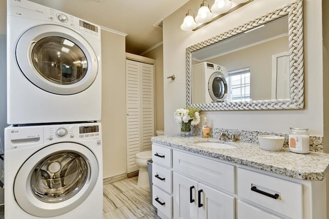 clothes washing area with stacked washer and dryer, ornamental molding, and sink