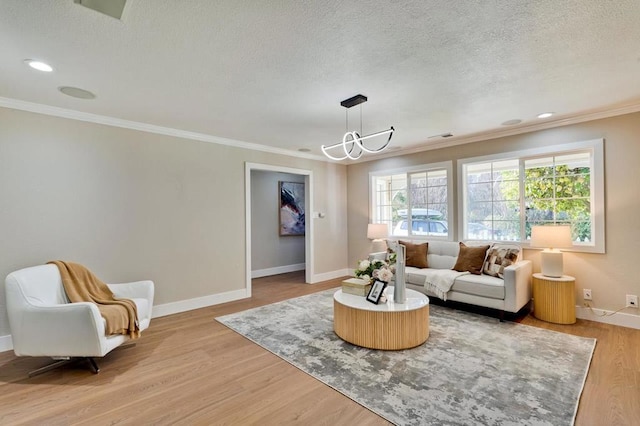 living room featuring crown molding, a notable chandelier, a textured ceiling, and light hardwood / wood-style flooring