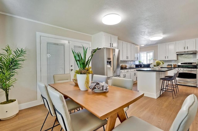 dining space featuring crown molding, french doors, a textured ceiling, and light wood-type flooring