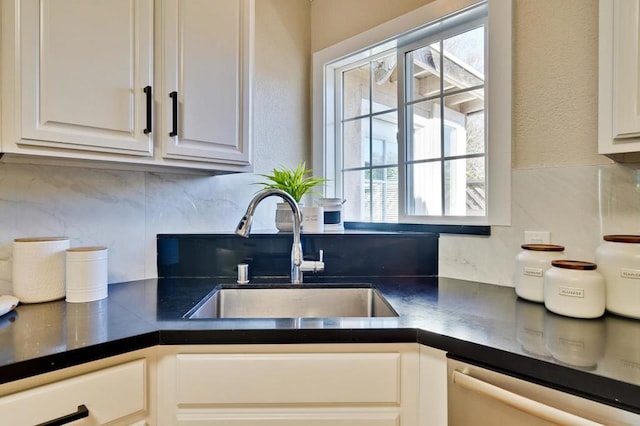 kitchen with stainless steel dishwasher, sink, decorative backsplash, and white cabinets