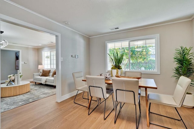 dining area with ornamental molding and light wood-type flooring