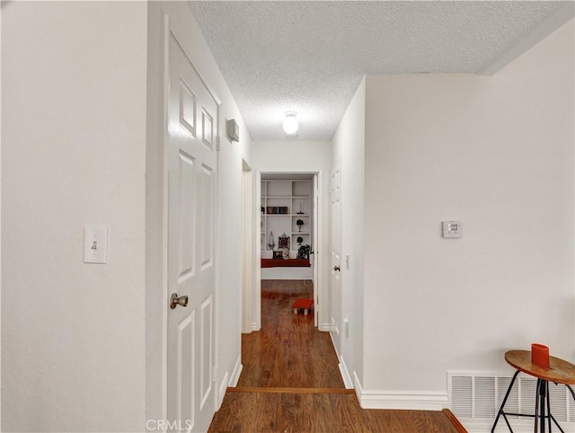 hall featuring a textured ceiling and dark wood-type flooring