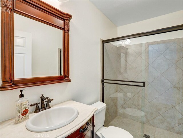 bathroom with toilet, an enclosed shower, and vanity