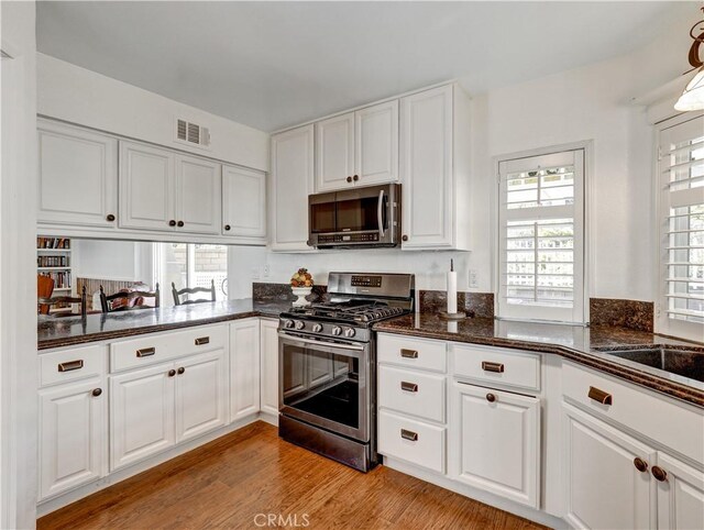 kitchen featuring appliances with stainless steel finishes, white cabinetry, and light hardwood / wood-style flooring