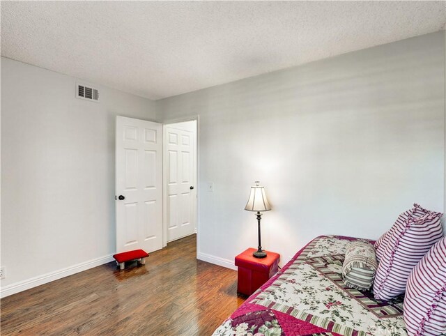 bedroom with a textured ceiling and dark hardwood / wood-style floors