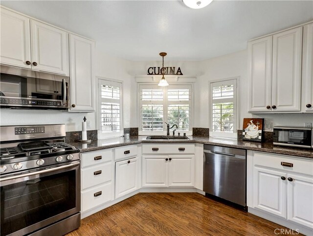 kitchen with stainless steel appliances, decorative light fixtures, dark wood-type flooring, white cabinets, and sink