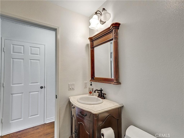 bathroom featuring toilet, wood finished floors, and vanity