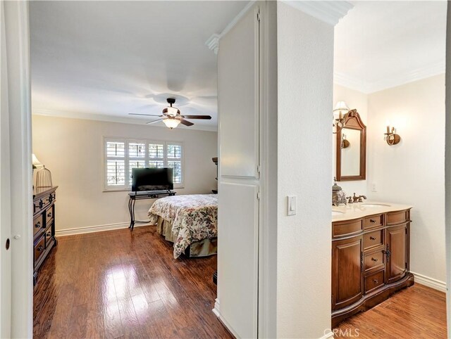 bedroom with dark wood-type flooring, ceiling fan, ornamental molding, and sink