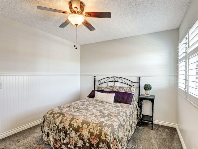 carpeted bedroom featuring a wainscoted wall and a textured ceiling