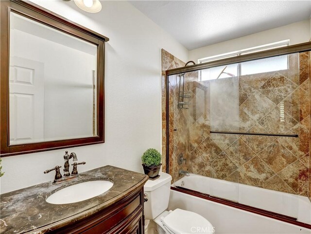 full bathroom with toilet, bath / shower combo with glass door, and vanity