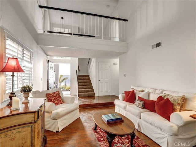 living area with a wealth of natural light, wood finished floors, visible vents, and stairs