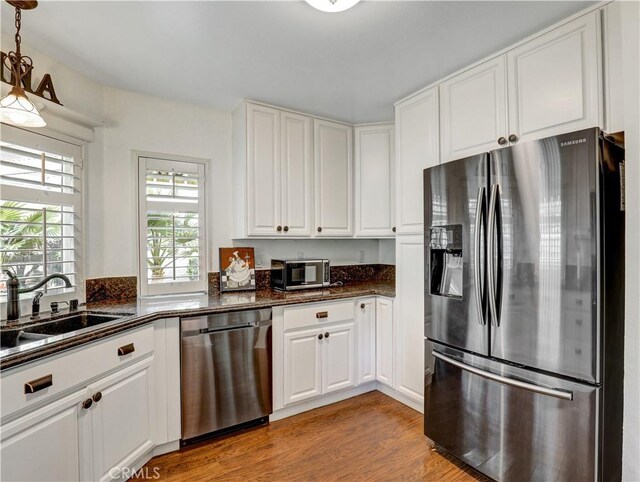 kitchen featuring decorative light fixtures, sink, light wood-type flooring, appliances with stainless steel finishes, and white cabinets