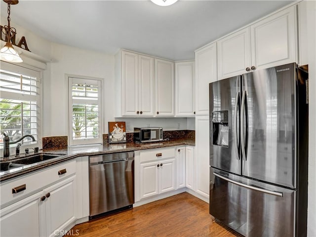 kitchen with stainless steel appliances, light wood-type flooring, a sink, and white cabinets