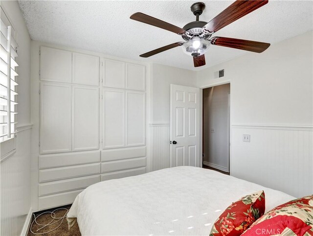 bedroom with ceiling fan, multiple windows, and a textured ceiling