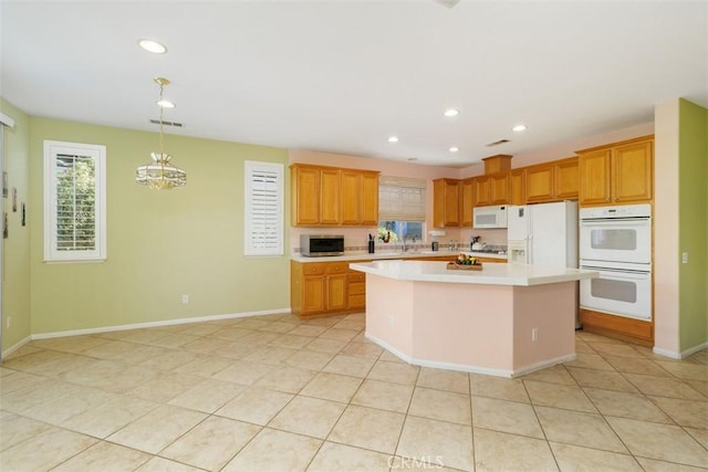 kitchen with light tile patterned floors, white appliances, decorative light fixtures, and a center island