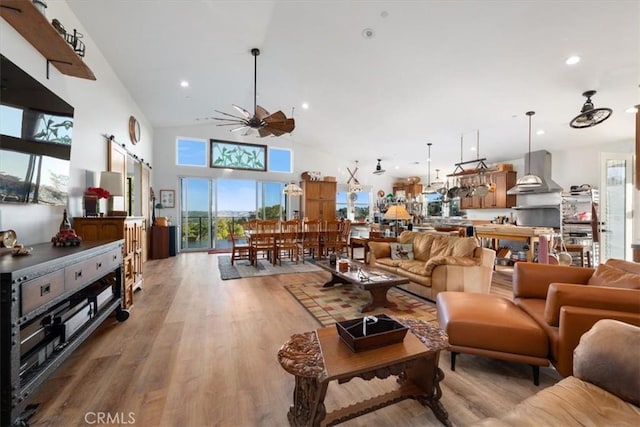 living room featuring high vaulted ceiling, light hardwood / wood-style floors, and ceiling fan