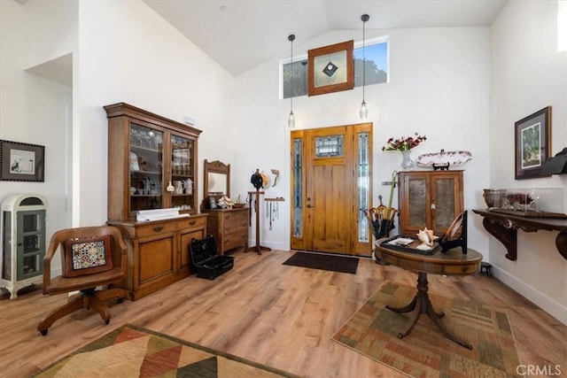 entrance foyer with high vaulted ceiling and light hardwood / wood-style flooring