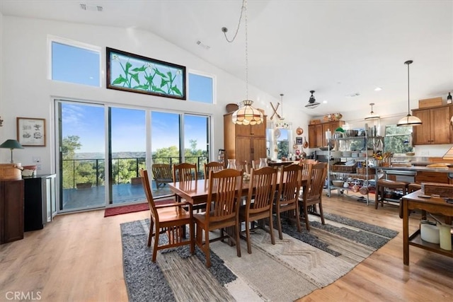 dining area featuring high vaulted ceiling and light hardwood / wood-style flooring