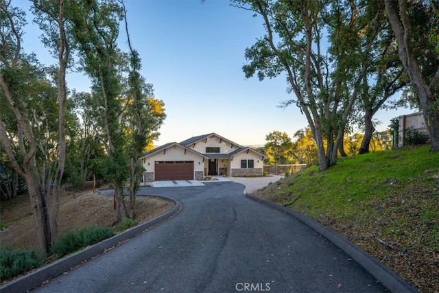 view of front of home with a garage, stone siding, and driveway