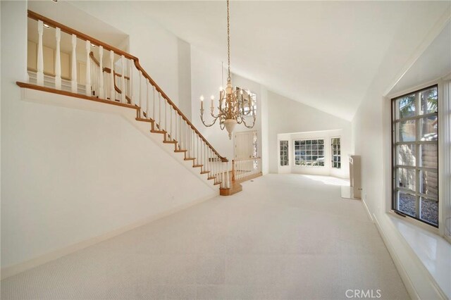 unfurnished living room featuring carpet flooring, high vaulted ceiling, and a notable chandelier