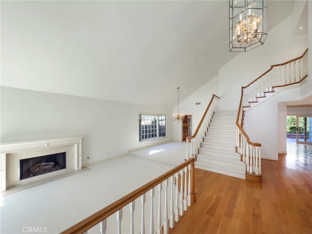 staircase with a premium fireplace, hardwood / wood-style flooring, a chandelier, and a wealth of natural light